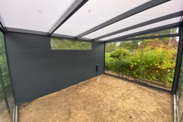 Binnen aanzicht van het dak de achterwand en een glazen schuifwand in een vrijstaande tuinkamer in Hoogeloon
